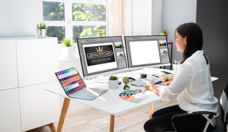 woman at computer with multiple monitors working on graphic designs