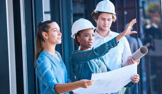 Woman in hard hat going over plans with two other individuals
