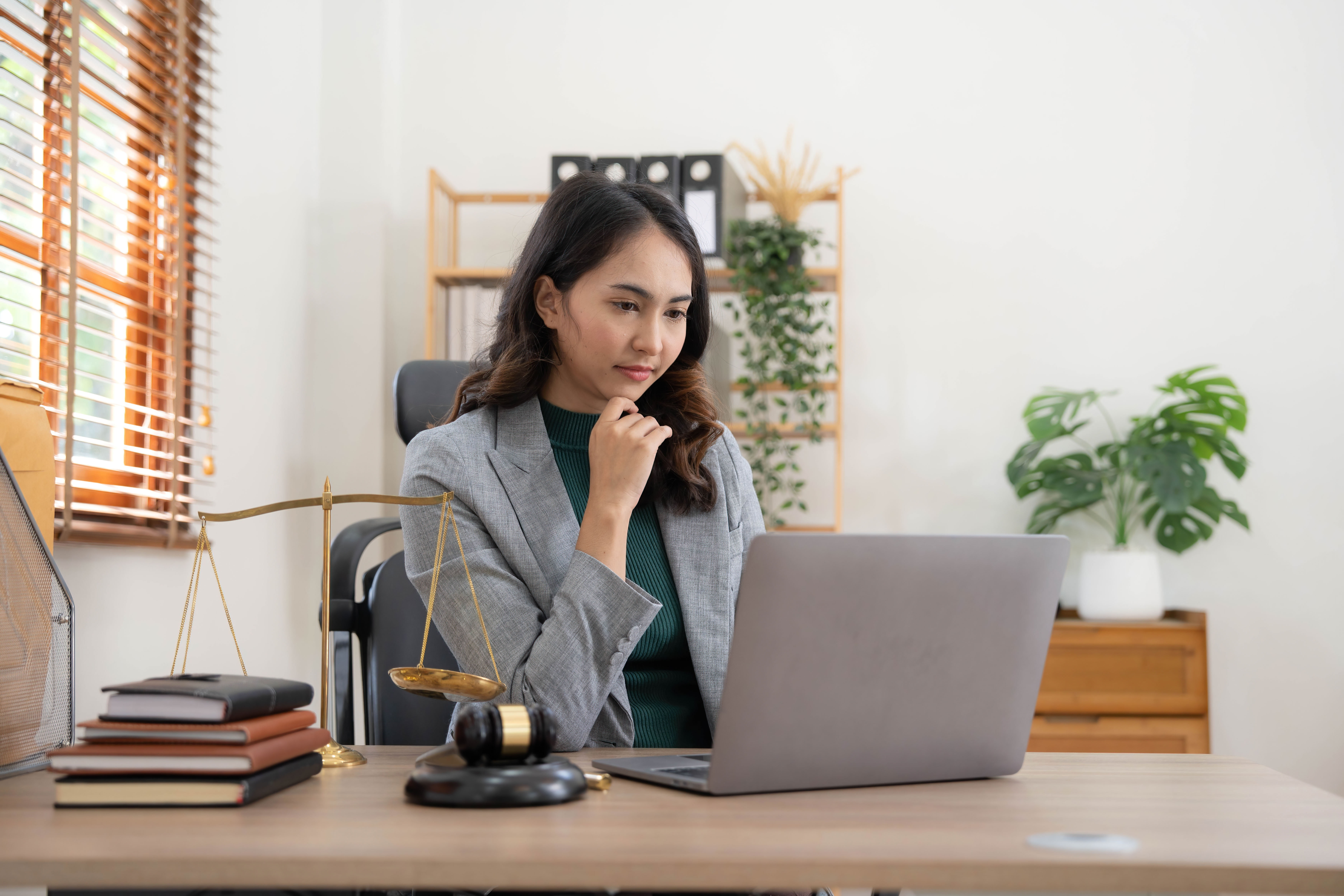 Woman in business suit sitting at a laptop next to a gavel.