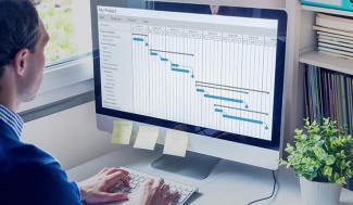 man sitting at a computer working on a Gant chart.