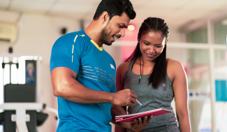 woman going over chart with male personal trainer