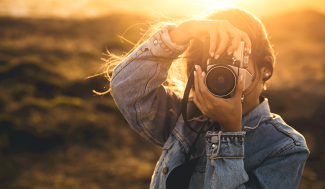 woman with a camera up to her face backlit by the sun