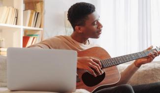 male playing guitar in home