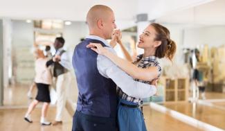 couple practicing ballroom dancing in a classroom